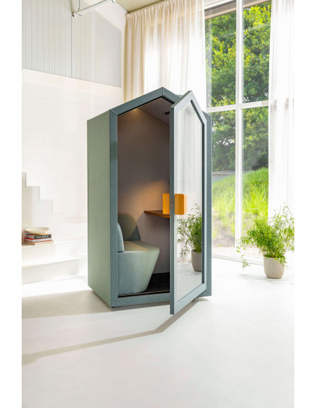 Акустична шумоизолираща кабина Cottage Pod в домашна среда с отворена врата пред голям прозорец